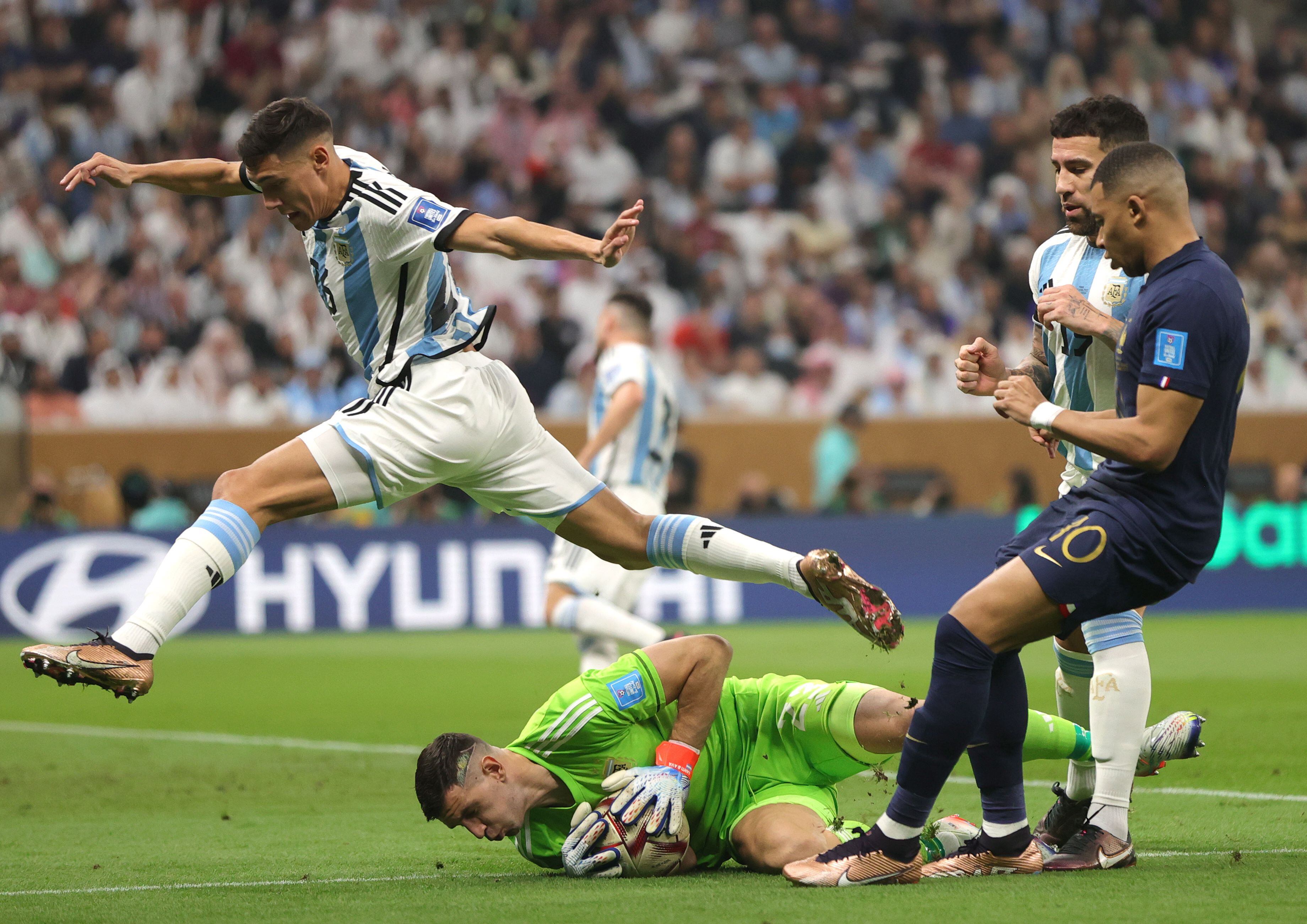 El protero argentino Damián Martínez ataja el balón en una ocasión del francés Kylian Mbappé. 