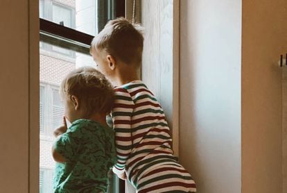 Dos niños miran por la ventana.