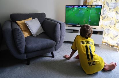 Un niño ve un partido de fútbol en la tele.