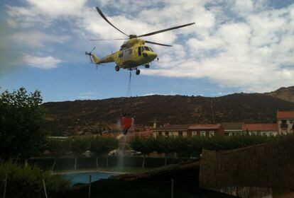 Un helicóptero extrae agua de una de las piscinas de la zona para intentar apagar el incendio forestal intencionado entre las localidades de Valdemaqueda y Robledo de Chavela.