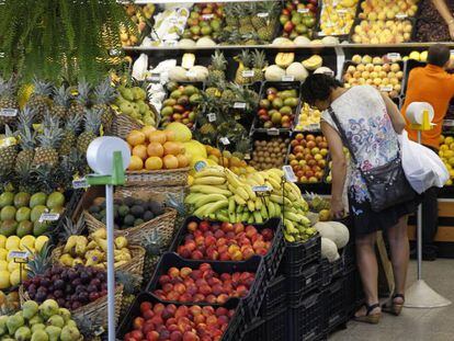 Una mujer elige fruta en un mercado.