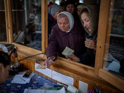 Mujeres ucranias muestran su identificación dentro de una iglesia para recibir ayuda humanitaria en Bucha, en las afueras de Kiev, este martes.