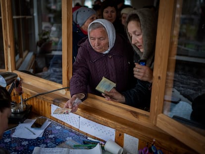 Mujeres ucranias muestran su identificación dentro de una iglesia para recibir ayuda humanitaria en Bucha, en las afueras de Kiev, este martes.