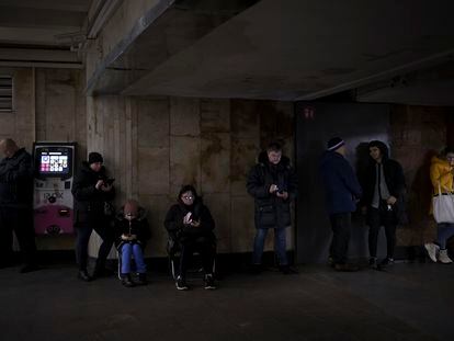 Un grupo de ciudadanos mira sus teléfonos móviles mientras se refugian en una estación de metro de Kiev durante una alarma antiaérea en diciembre de 2022.