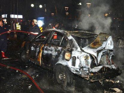 Bomberos tratan de apagar un coche quemado por la explosi&oacute;n.