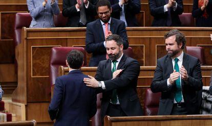 El presidente de Vox, Santiago Abascal, da una palmada en la espalda en señal de reconocimiento al portavoz de Unión del Pueblo Navarro (UPN) en el Congreso, Sergio Sayas, tras su intervención.