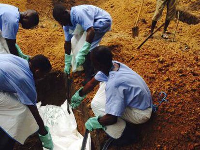 Cuatro voluntarios del personal sanitario entierran a una víctima del ébola en Sierra Leona.