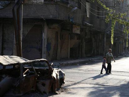 Un hombre y un ni&ntilde;o caminan por la zona rebelde de Ain Tarma, en Ghuta, al este de Damasco.
