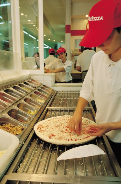 Una mujer cocina en una tienda de Telepizza.