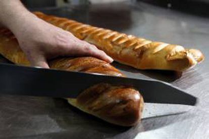 Un repostero corta una barra de pan en una pastelería de España. EFE/Archivo