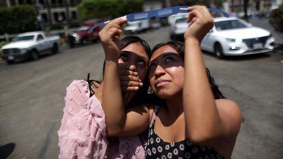 Jóvenes observan el eclipse solar en Ciudad de México.