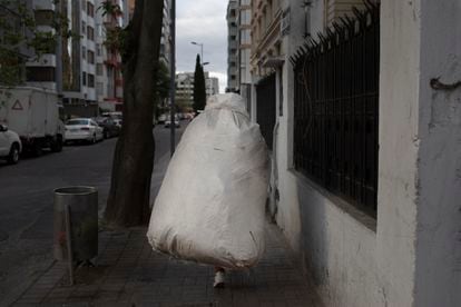 The recycler Elizabeth Pulupa carries a sack full of garbage to the truck through the streets of Quito, in August 2019. 