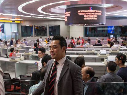 Un hombre posa para hacerse una fotografía frente al panel electrónico del hall en la Bolsa de Hong Kong. EFE/Archivo