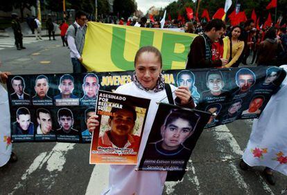 Una mujer sostiene dos fotografías de desaparecidos durante una marcha por las calles del centro de Bogotá (Colombia).