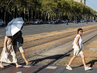 Tres personas cruzan la Diagonal de Barcelona, esta semana, en plena ola de calor y protegiéndose del sol.