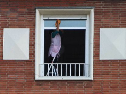 Una empleada del hogar limpia la ventana de un piso. / ÁLVARO GARCÍA