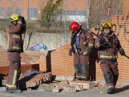 Un grupo de bomberos desescombra el muro caído en Terrassa.