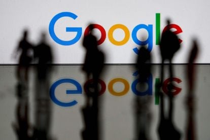 Varias personas pasan junto a un logo luminoso de Google.