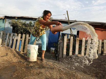 Una mujer arroja agua sucia afuera de su casa en Callao, Per&uacute;