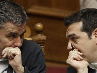 Euclides Tsakalotos (izquierda) habla con el primer ministro Alexis Tsipras durante la aprobaci&oacute;n de las subidas de impuestos reclamadas por la troika.