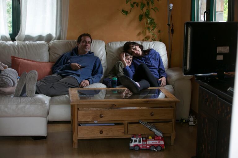 Una familia viendo la televisión en el salón de su casa.