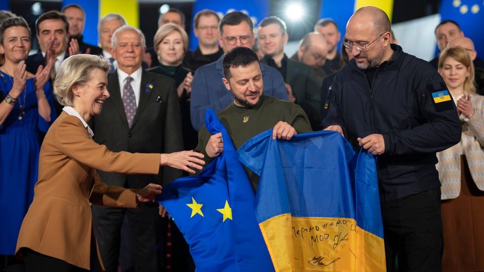 El presidente ucranio, Volodímir Zelenski, sostiene banderas de su país y de la UE, junto a la presidenta de la Comisión,  Ursula von der Leyen, y el primer ministro ucranio, Denis Shmihal, en Kiev, el pasado 2 de febrero.
