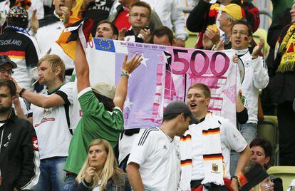La afición teutona sostiene una tela que reproduce un billete de 500 euros.