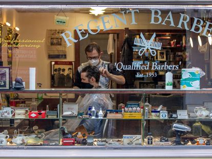 Un peluquero con mascarilla atiende a un cliente en Dublín este lunes.