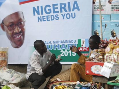 Dos vendedores junto a un cartel promocional del presidente nigeriano Buhari.