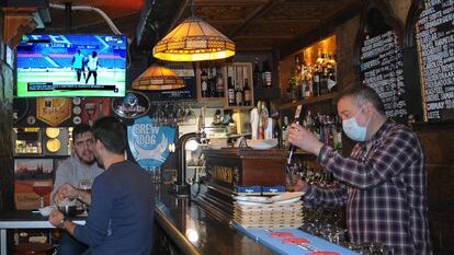Víctor Rey sirve unas cervezas en su bar, El rincón del Greco. De fondo, un informativo de LaLiga Santander. 