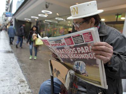 Un limpiabotas lee una portada que refleja la derrota argentina ante Chile.
