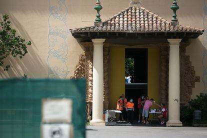 Un trabajador de la Cruz Roja toma la temperatura a una persona en la puerta de un pabellón para sin techo de Barcelona.