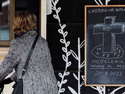 Una mujer observa un cartel colocado en una cafetería de Valencia