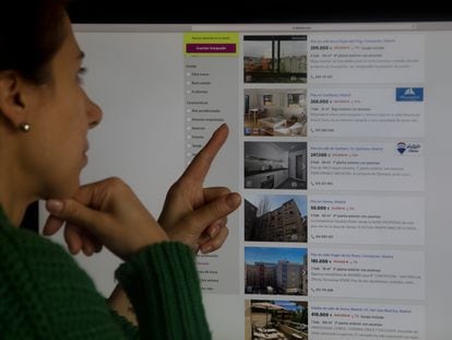 Una mujer consulta un portal inmobiliario con pisos rebajados, en Madrid.