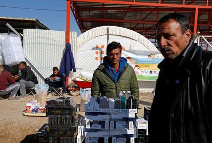 Ahmed Mohamed Yassin, del distrito de Aden, junsto a su puesto de cigarrillos mientras espera clientes en el campamento Khazer. 'Cuando vivía en Mosul vendía cigarrillos, la vida era buena, los mercados estaban en auge. Pero después de Daesh en 2014, aplicaron impuestos a todos los sectores bajo el pretexto de la sharía'.