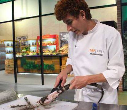 Un cocinero pela la cola de una iguana ya cocida el domingo en la televisión de El Salvador.