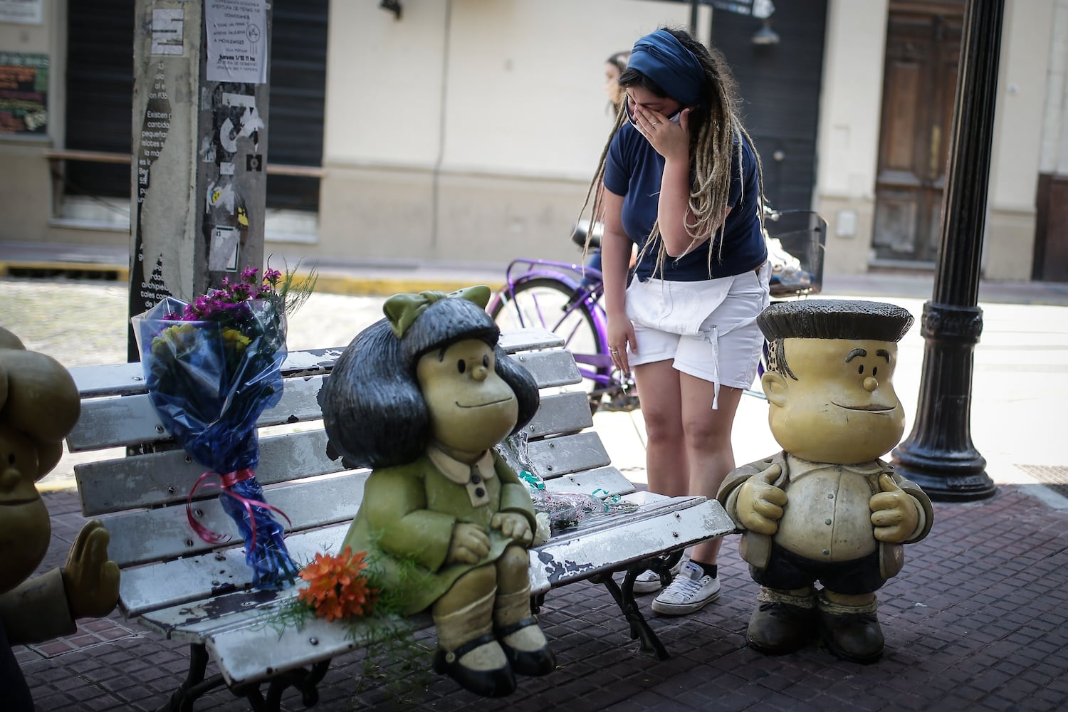 Una mujer llora este miércoles mientras deja flores en la estatua de los personajes de Quino en Buenos Aires.