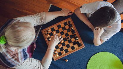 Una abuela enseñando a su nieto a jugar al ajedrez.