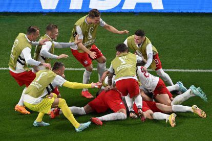 Los jugadores de Polonia abranzan a Robert Lewandowski (cubierto) después de que el jugador del Barcelona marcara el gol de la victoria ante Arabia Saudí.