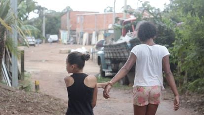 Dos niñas caminan junto a la huerta comunitaria de la Vila Nova Esperança.