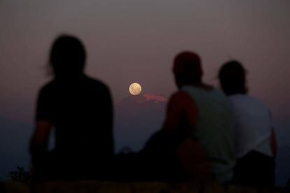 Un grupo de personas observa la superluna subiendo tras la cordillera de Los Andes en Santiago (Chile). 