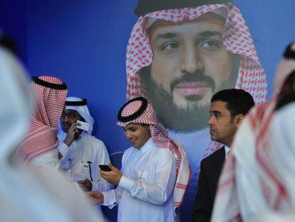 Un grupo de saud&iacute;es habla junto a un p&oacute;ster del pr&iacute;ncipe heredero Mohammed bin Salman durante el Foro Misk, celebrado esta semana en Riad.