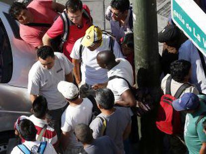 Un grupo de hombres ofrece sus servicios a un reclutador de braceros junto a la plaza Elíptica.