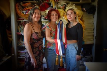 Ingrid Albornoz (left), Marta Gatica and Arety Alvarado, members of the Revolutionary Textile Union, show the sash they have made for President Gabriel Boric, on March 9, 2022 in Santiago, Chile.