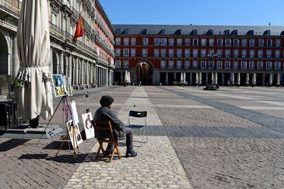 Un caricaturista espera a que llegue algún cliente en la Plaza Mayor de Madrid.
