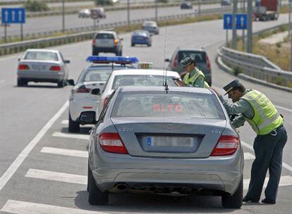 Un conductor recibe el boletín de denuncia entre el coche camuflado de la Guardia Civil y un vehículo patrulla.