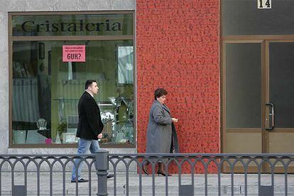 Pilar Elías, viuda de Ramón Baglietto, acompañada de un escolta, pasa por delante de la cristalería Aldako.