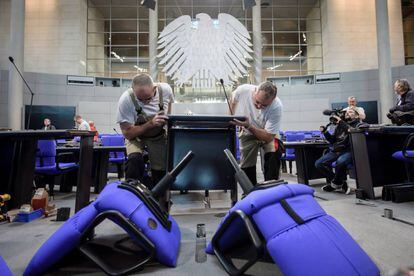 Varios operarios desmantelan los sillones del hemiciclo del Parlamento alemán en Berlín (Alemania).