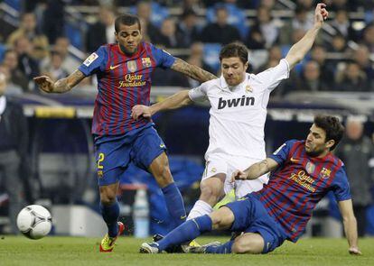 Los azulgrana Dani Alves y Cesc Fàbregas disputan un balón con el jugador del Real Madrid, Xabi Alonso.