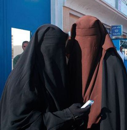 Dos mujeres en Túnez vestidas con 'niqab' miran su teléfono móvil.